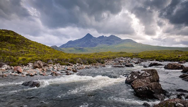 Sgrr nan Gillean silueti Sligachan nehrine hükmediyor. Kızıl Tepeler 'de (Red Cuillin), İskoçya yazının kasvetli öğleden sonrasında çekilen sahne.