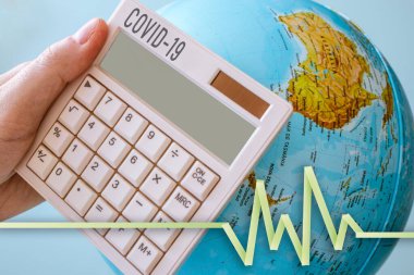 Bir hesap makinesinin fotoğrafı, COVID-19 başlıklı, hayati bir işareti olan ve arka planda bir dünya olan. Herhangi bir virüs için mükemmel, salgın teması.