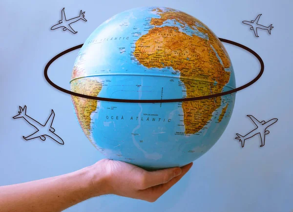 Earth ball hold by a hand with few plane drawings around. Perfect for travel, international or holidays themes.