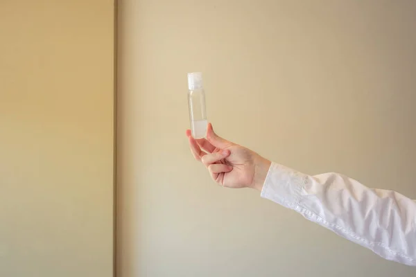 Sıvı bir şişeyi tutan el. Belirli bir sıvıyı gösteren dezenfektanların kullanımını temsil etmek için kullanılabilir.