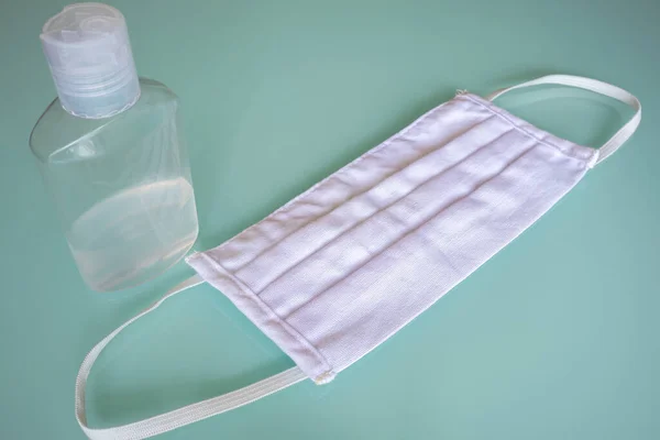 Bazı virüs ve bakterileri önlemek için temizlik, önlem ve tıbbi malzemeleri temsil eden kristal bir masanın üzerindeki yüz maskesi ve dezenfektan.