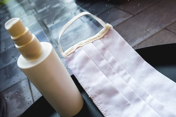 Evde yağmurlu bir günde pencerenin yanında yüz maskesi ve dezenfektan..