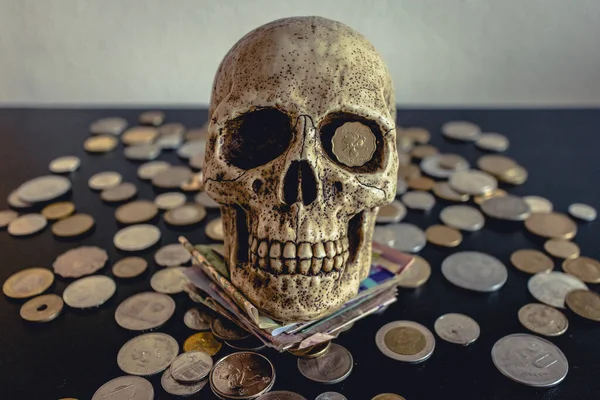 Siyah bir masanın üzerinde farklı madeni paralar olan bir kafatası. Korsanlar gibi. Ekonomik kriz, ölüm vb.