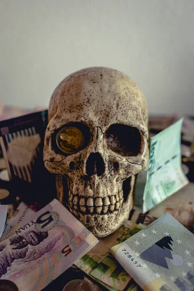 Siyah bir masanın üzerinde farklı madeni paralar olan bir kafatası. Korsanlar gibi. Ekonomik kriz, ölüm vb.