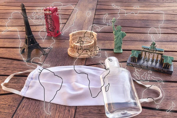 Farklı uluslararası anıtlara sahip maske ve dezenfektan ve bir harita çizimi.