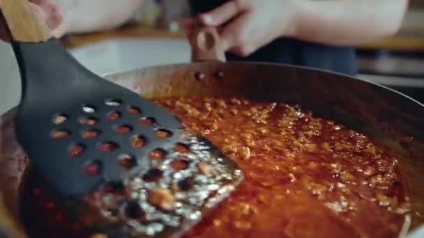 Шеф-повар готовит колбасный соус в кастрюле с лопаткой. — стоковое видео