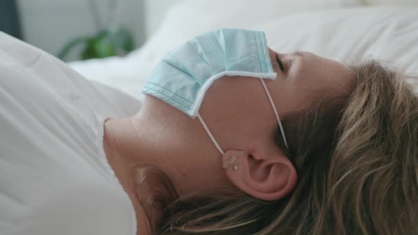 Die Frau in der Maske, die im Bett liegt, hat traurige und traurig kranke Augen, Virus — Stockvideo