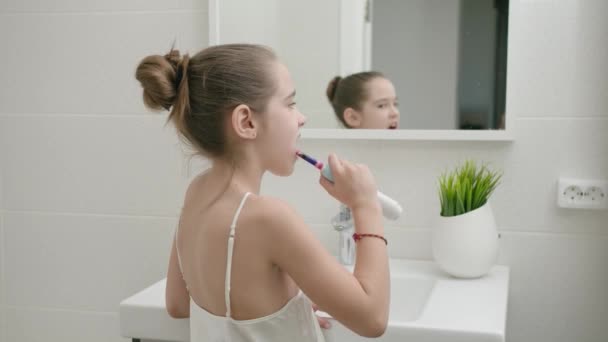 Mooi Kaukasisch meisje poetst haar tanden in de badkamer om gezondheid te voorkomen — Stockvideo