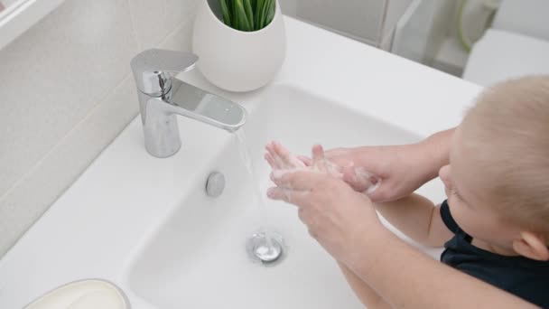 Мама миє руки дитини з милом, захищаючи від коронавірусу, щоб запобігти COVID — стокове відео