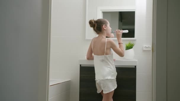 Güzel beyaz kız sağlığını korumak için dişlerini banyoda fırçalıyor. — Stok video