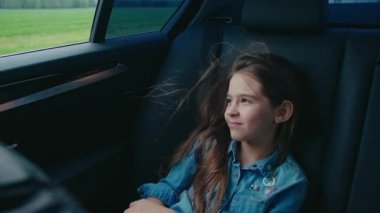 Arabayla seyahat eden bir kız, temiz hava almak için pencereyi açıyor.