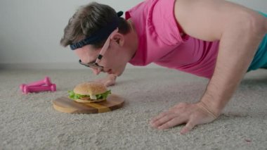 Komik adam yerden itiyor ve hamburger yemeye çalışıyor. Yavaş çekim