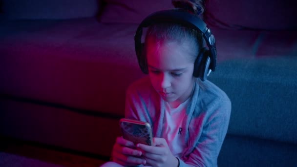 一个漂亮的女孩在霓虹灯下玩电脑游戏。智能手机中的电子竞技 — 图库视频影像