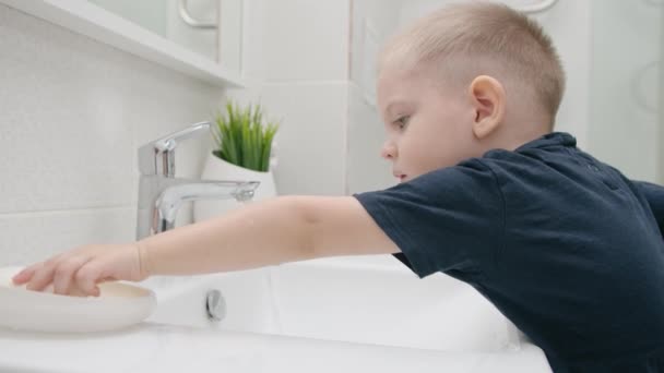 꼬마는 싱크대 위로 비누로 손을 씻는다. COVID-19 로부터의 보호 — 비디오