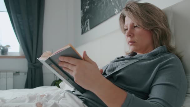 Femme couchée sur le lit malade et lisant un livre et éternuant coronavirus — Video