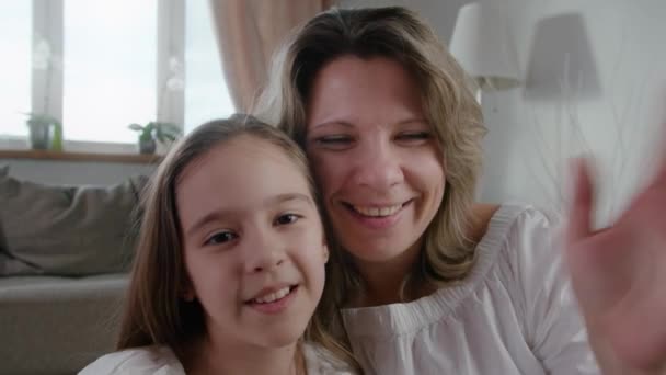 Glad kaukasiska familj mamma och söt liten unge dotter skratta använda smartphone på distans prata roligt ansikte och le slow motion — Stockvideo