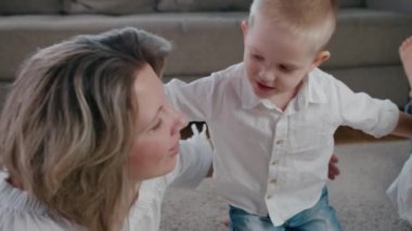 Güzel, mutlu bir kadın ve genç bir kız ve erkek, anne, kız ve oğul güneşli bir günde evin içinde sarılıp öpüşüyorlar. Yavaş çekim