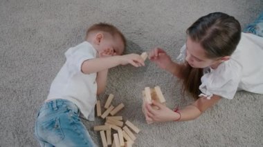 Beyaz kız ve oğlan güneşli bir günde evde jenga oynuyorlar, birlikte gülüyorlar ve eğleniyorlar. Üst görünüm açısı