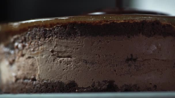 Le chef prépare un gâteau pour un dessert sucré et le remplit d'une fine couche de glaçure au chocolat, qui coule le long de ses bords fermer — Video