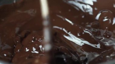 Şef sıcak kahverengi çikolatayı spatulayla yoğurur.