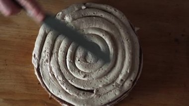 Pasta şefi kremayı tüpten pasta katmanına dairesel bir hareketle sıkıyor.