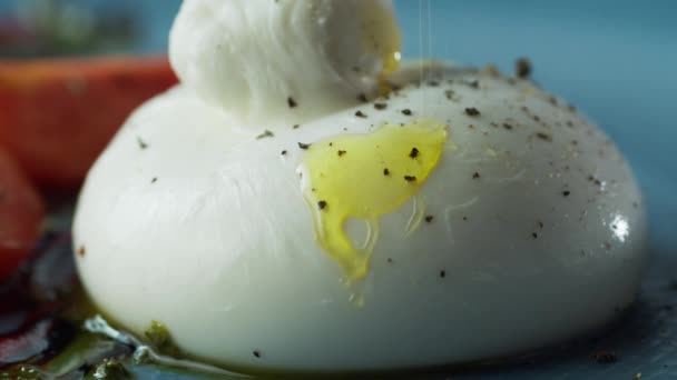 Close-up of olive oil flowing and dripping on a delicious white cheese found in herbs and vegetables Video Clip