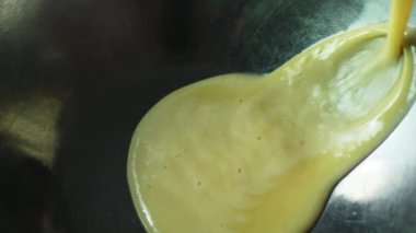Bir şefin miksere kırbaç atmak için metal bir kaseye yumurta karıştırdığı yakın plan.