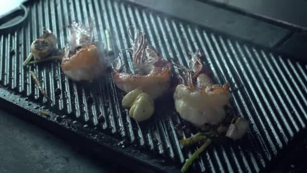 Шеф-повар посыпать масло на креветки, которые на гриле с травами и чесноком в густой дым — стоковое видео