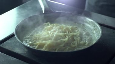 Şef makarnayı kremalı sosla tavaya koyar, maşayla carbonara hazırlar.