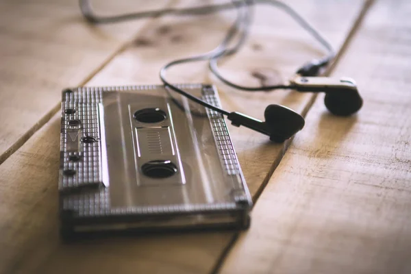 Tahta bir masanın üzerinde yatan kulaklık ile müzik kaset — Stok fotoğraf