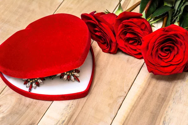 Necklace in a box in the form of a heart lies on a table with re — Stock Photo, Image