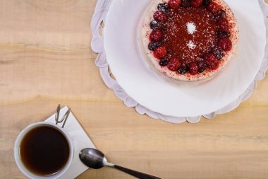 Pasta çilek bir tabak ve bir bardak çay ile üzerinde ahşap bir masa standı