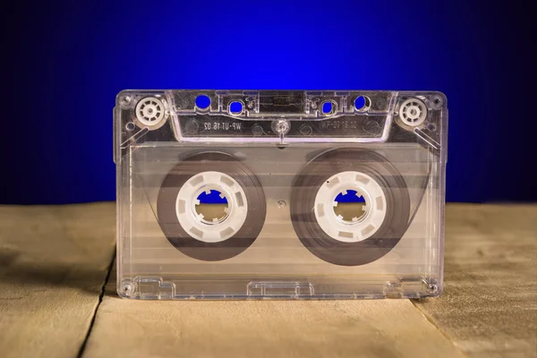 White audio cassette stands on a wooden table