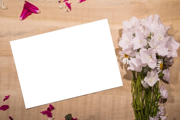 Hoja blanca de papel con un ramo de flores acostadas sobre una mesa —  Fotos de Stock