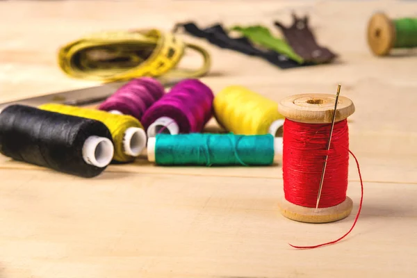 Red thread on a wooden spool with a needle — Stock Photo, Image