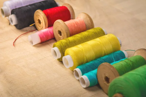 Sewing threads of different colors are laid out on a wooden tabl — Stock Photo, Image