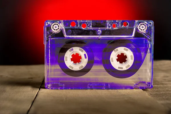 Cassette audio transparente sur une table en bois sur fond rouge — Photo