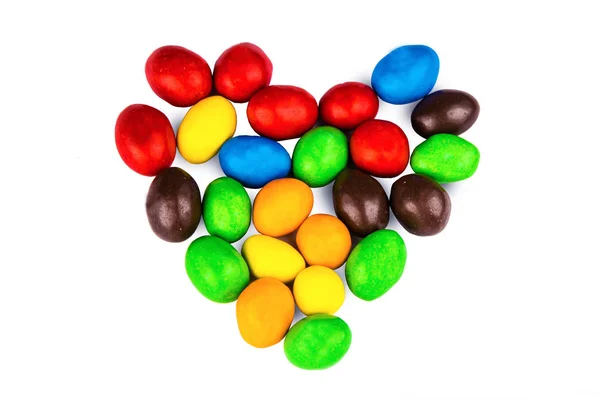 Multicolored candy dragees lined in the shape of heart on a whit Stock Picture