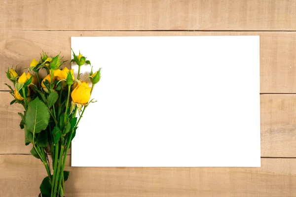 En bukett gula rosor ett vitt pappersark på en trä flik — Stockfoto