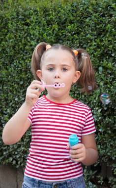 Küçük bir kız yaz parkta sabun köpüğü üfleme.