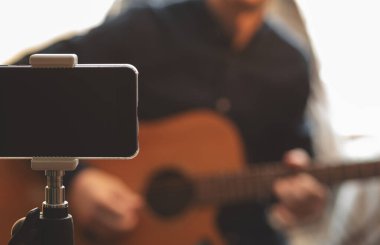 Akustik gitarlı ve şapkalı bir adam, karantina sırasında izleyiciler için canlı yayında canlı performans sergiliyor ve Coronavirus yüzünden kendini izolasyona zorluyor.