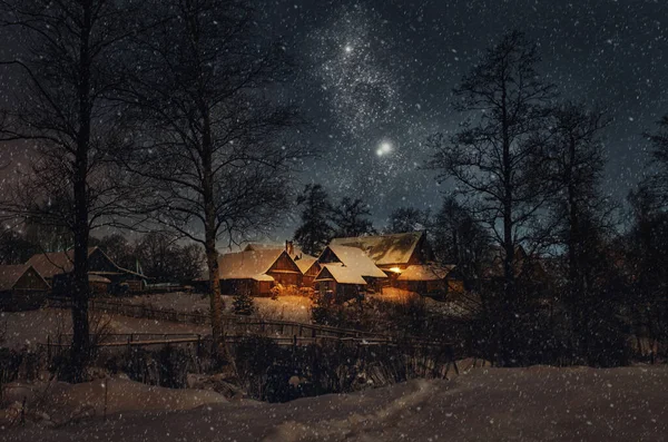 Güzel bir kış gecesi, Noel manzarası. Pencereden gelen sıcak ışıkla aydınlatılan karlı köy evlerinin manzarası. Yıldızlı gece ve Noel önsezisi.
