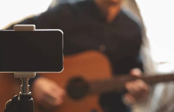 Akustik gitarlı ve şapkalı bir adam, karantina sırasında izleyiciler için canlı yayında canlı performans sergiliyor ve Coronavirus yüzünden kendini izolasyona zorluyor.