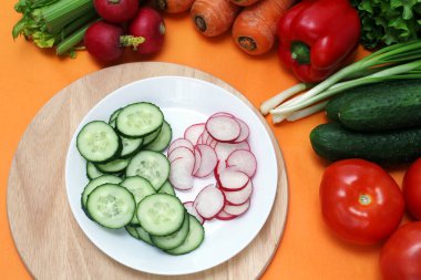 Masada taze sebzeler, dilimlenmiş salatalık ve turpların yanında.