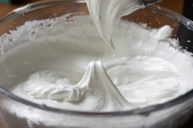 Açık bir cam kasede krema karıştırıcının karışımından çıkarıldığı gibi ortada sert bir zirve oluşturur.