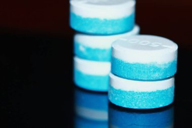 Beyaz ve mavi yuvarlak ilaç hapları.