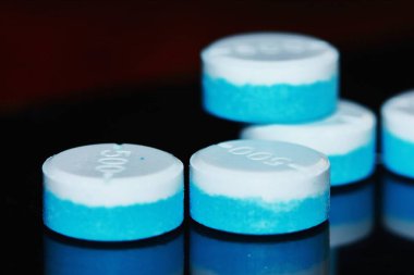 Beyaz ve mavi yuvarlak ilaç hapları.