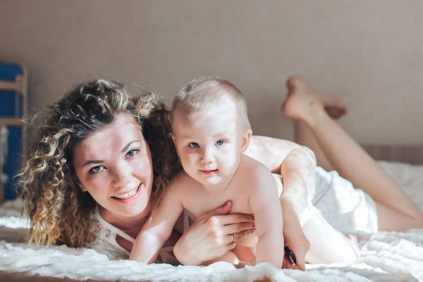 Mother and baby lie on bed — Stock Photo, Image