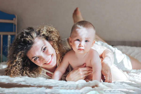 Mother and baby lie on bed — Stock Photo, Image
