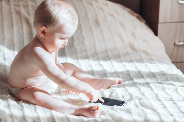 Bebé con el teléfono sentado en la cama — Foto de Stock